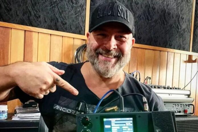 Mingau, de boné e sorrindo, em estúdio de gravação